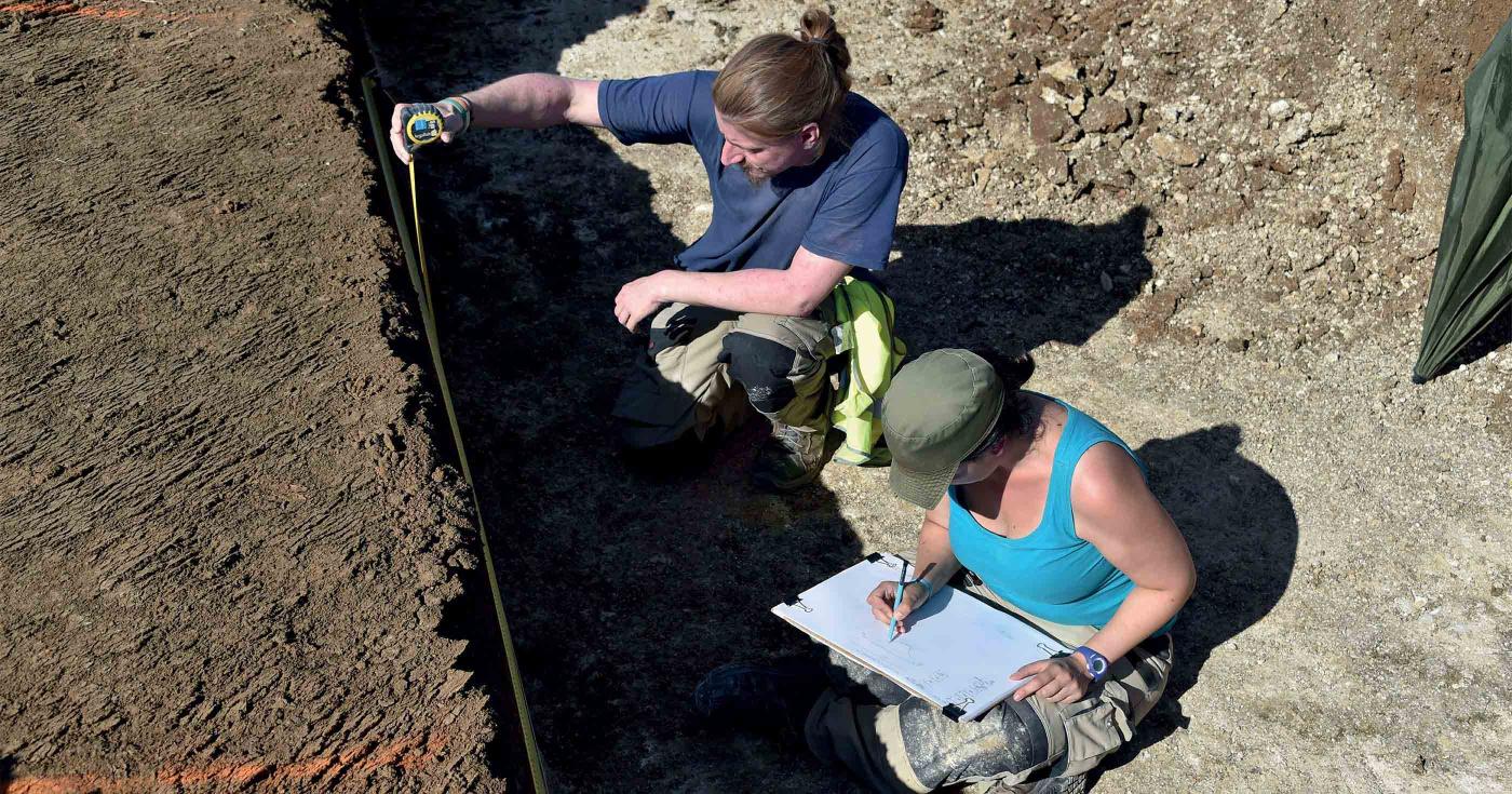Des archéologues sont en train de dessiner des vestiges archéologiques.
