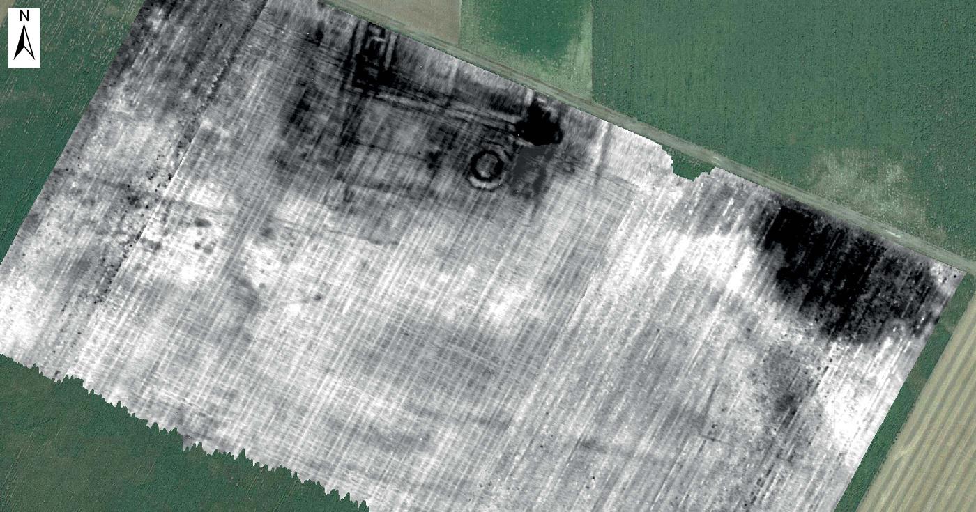 Le relevé géophysique en contraste de gris et noir est apposé sur la photo aérienne du champ.