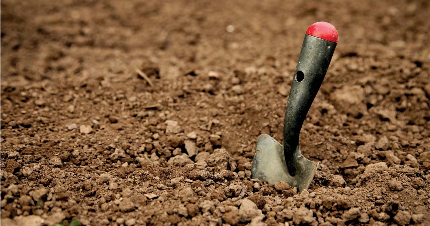 Une petite pelle à main est plantée dans la terre.