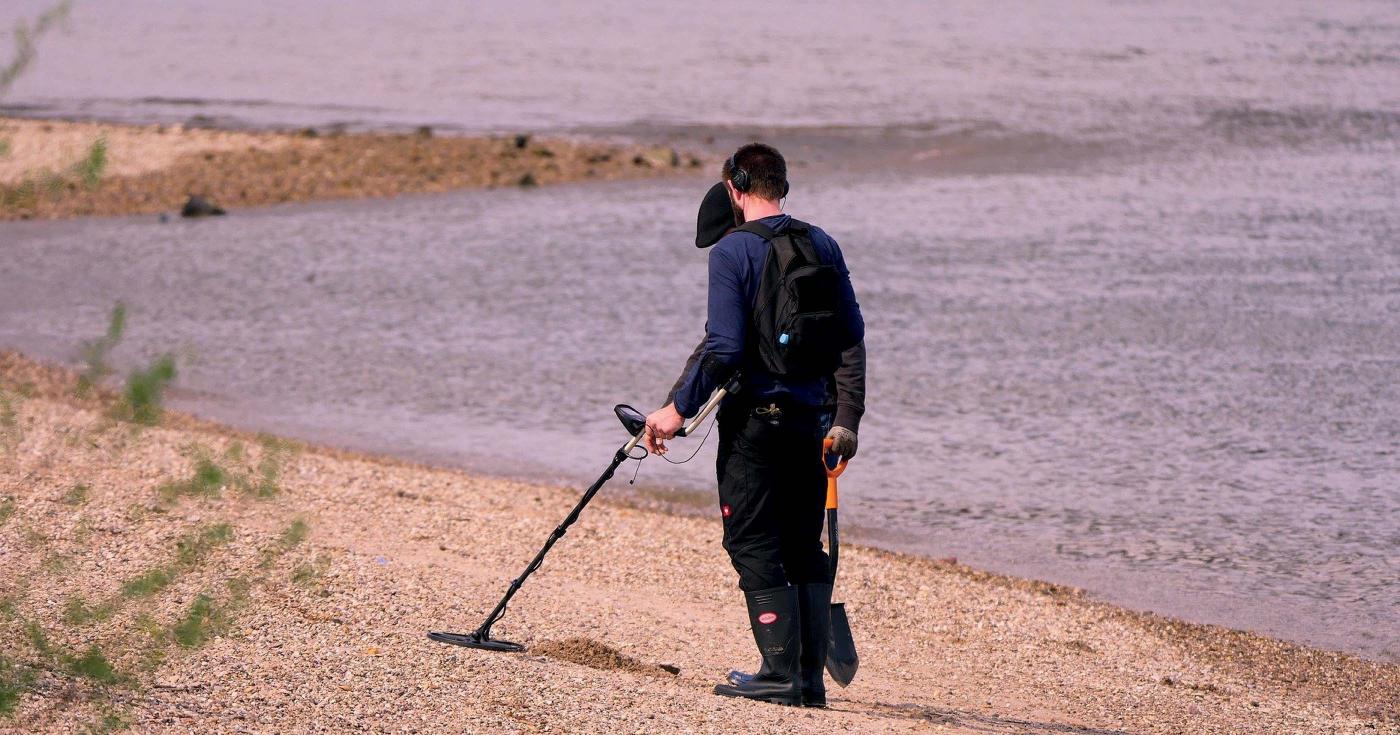 Un homme utilise un détecteur de métaux sur une plage.