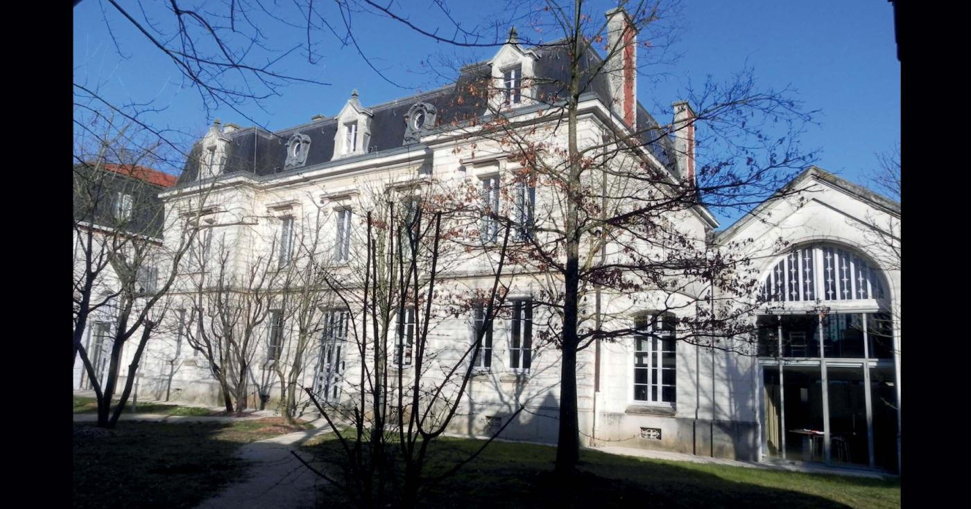 Bâtiment ancien derrière des arbres.