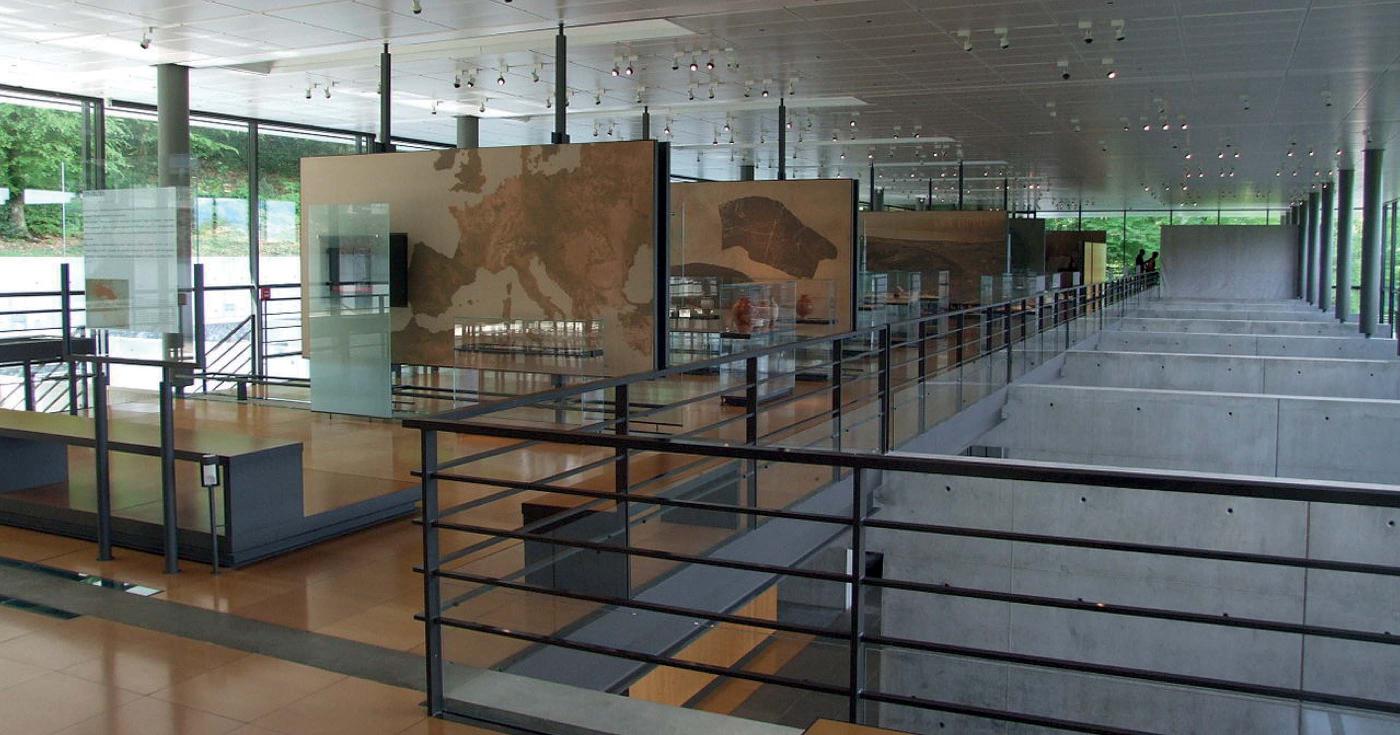 Vue d'une salle du Musée de Bibracte où l'on aperçoit des panneaux explictifs et des vitrines de mobilier.