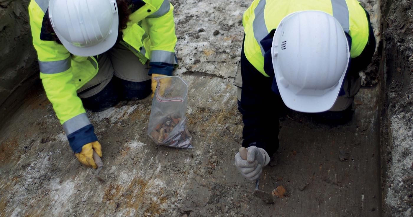Des archéologues sont en train de dégager des fragments de mobilier archéologique avec leur truelle.