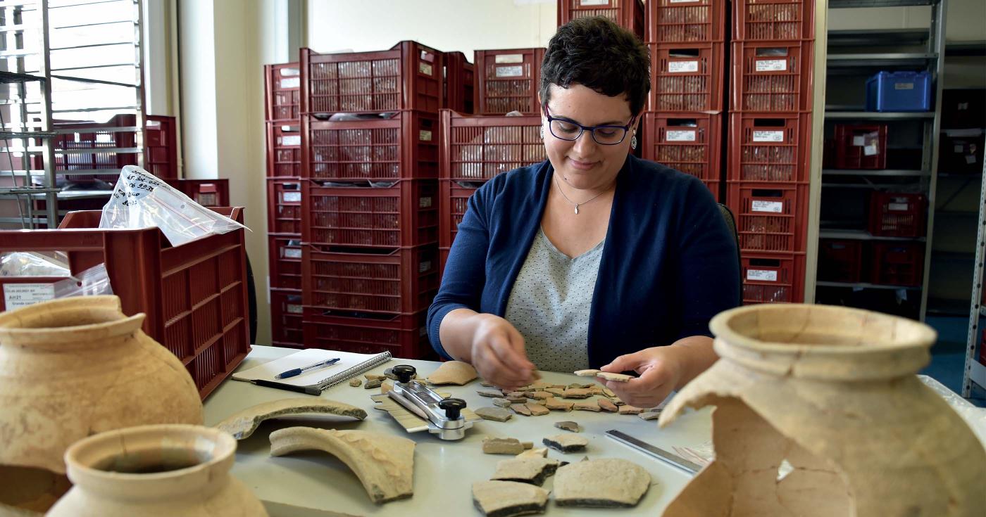 Une archéologue travaille au recollage des fragments de céramique.