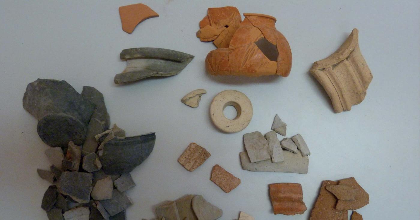 Des fragments de céramiques de différents types (couleurs et formes) sont éparpillés sur une table d'étude.