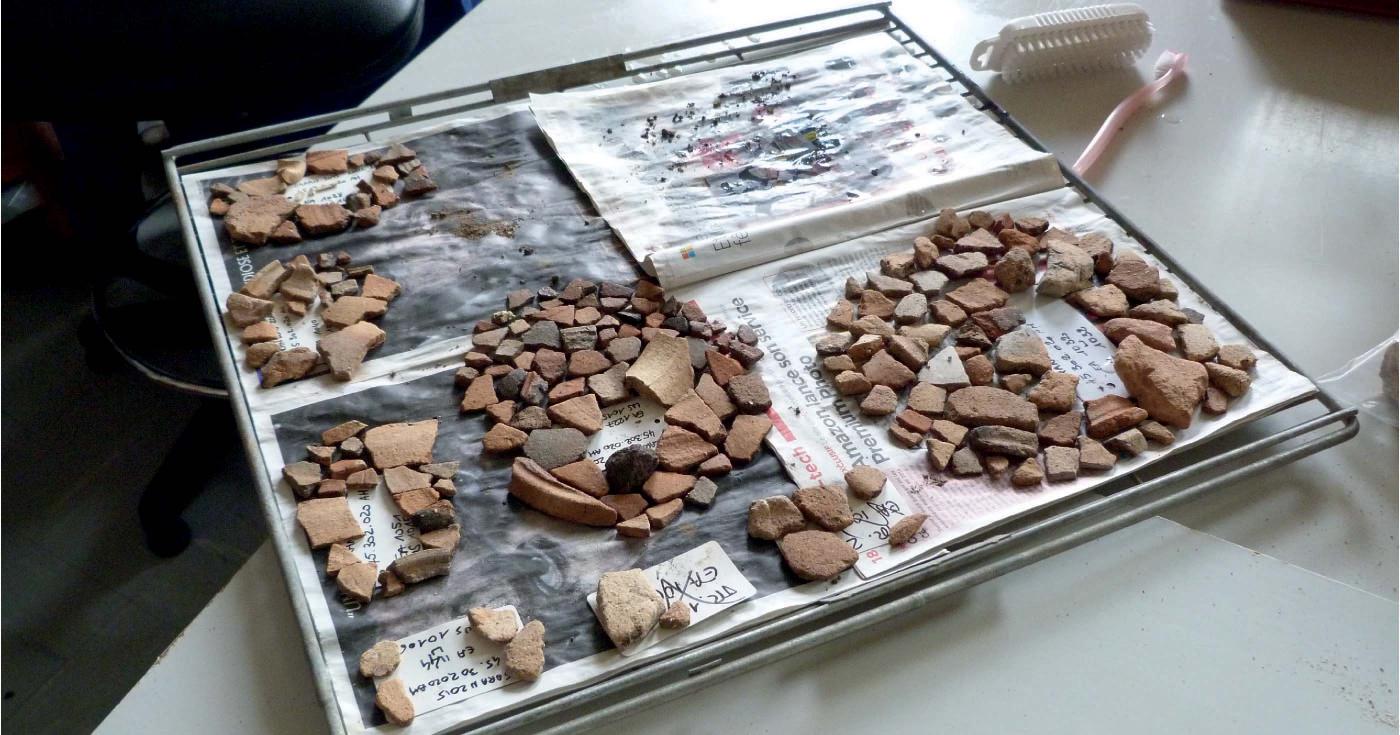 Des fragments de céramique sont posés sur du papier journal.