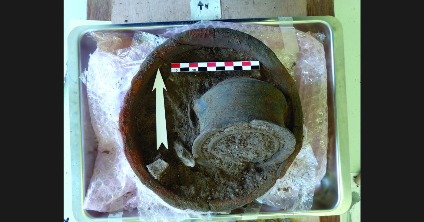 Des céramiques emboîtées et rempies de terre sont posées sur une table de laboratoire pour étude.