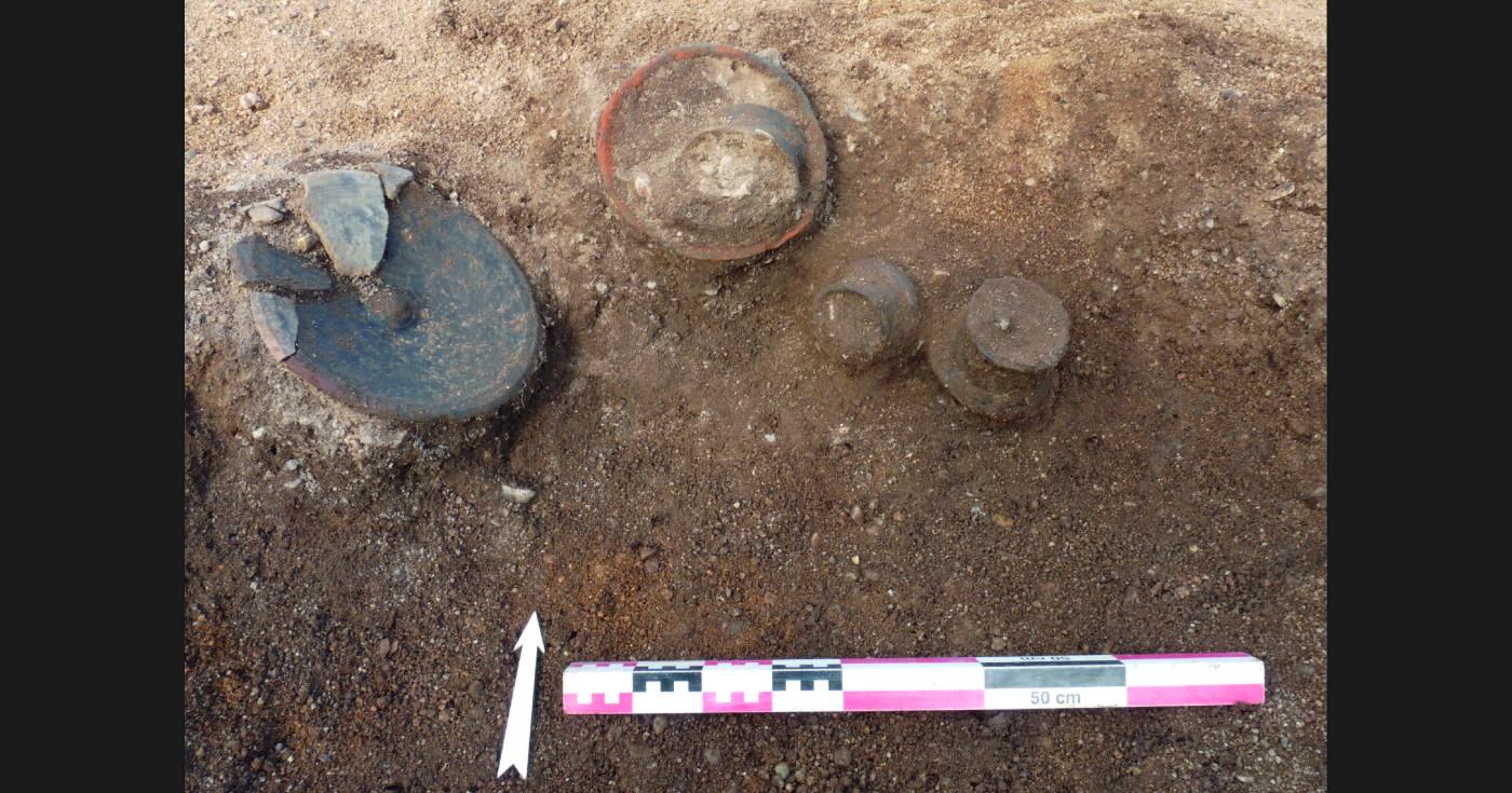 Dans une fosse creusée dans le sol sont posées plusieurs vases en céramique remplis de terre.