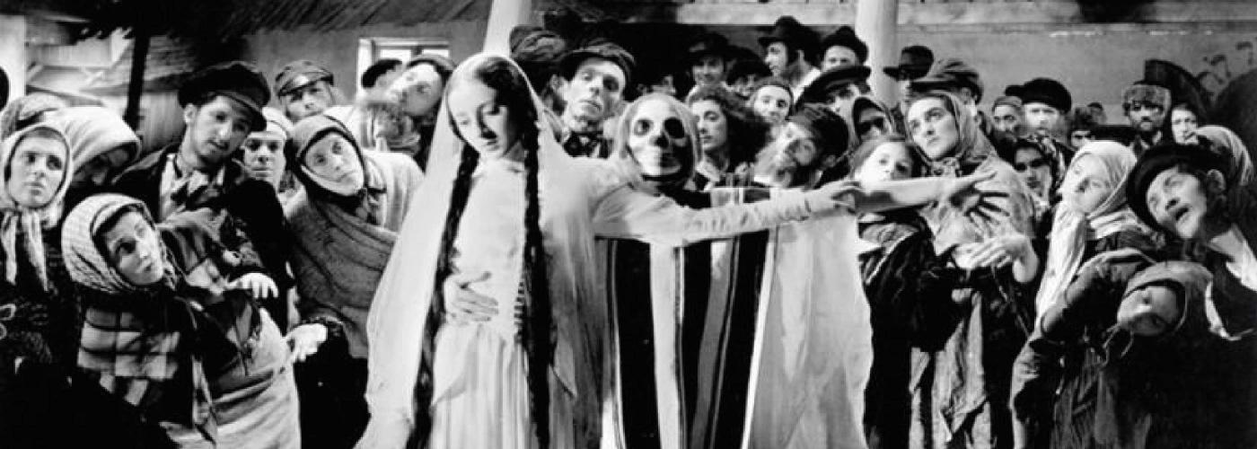 Photographie extraite d'un film : une jeune fille et un spectre sont entourés d'un groupe de villageois qui les observent.